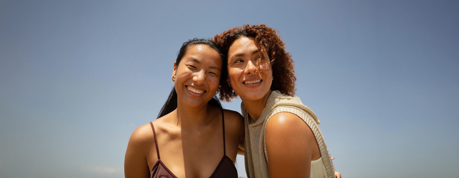Two women smiling with a blue sky behind them.
